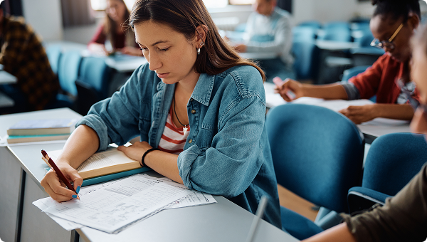 Studenten schreiben konzentriert in einem Klassenzimmer eine Prüfung.