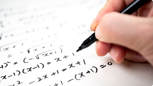 Hand schreibt mathematische Gleichungen mit einem Stift auf Papier.